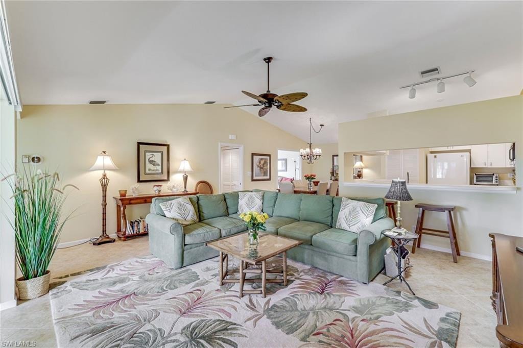 Vaulted ceilings highlight this living area featuring neutral-toned walls and tile flooring
