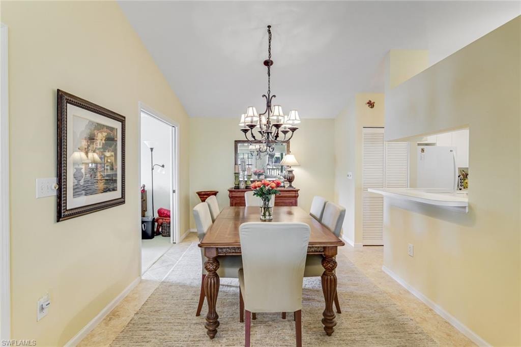 Dining area featuring a chandelier, tile flooring, and a pass-through window to the kitchen