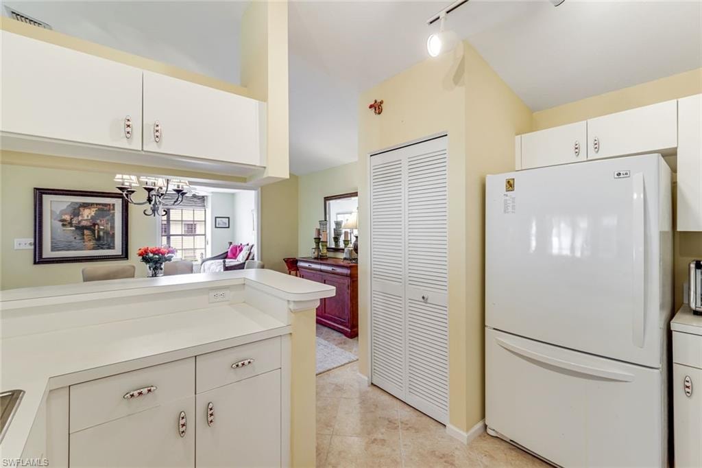 Kitchen featuring white cabinetry with brushed nickel hardware, light-toned countertops, and a white refrigerator