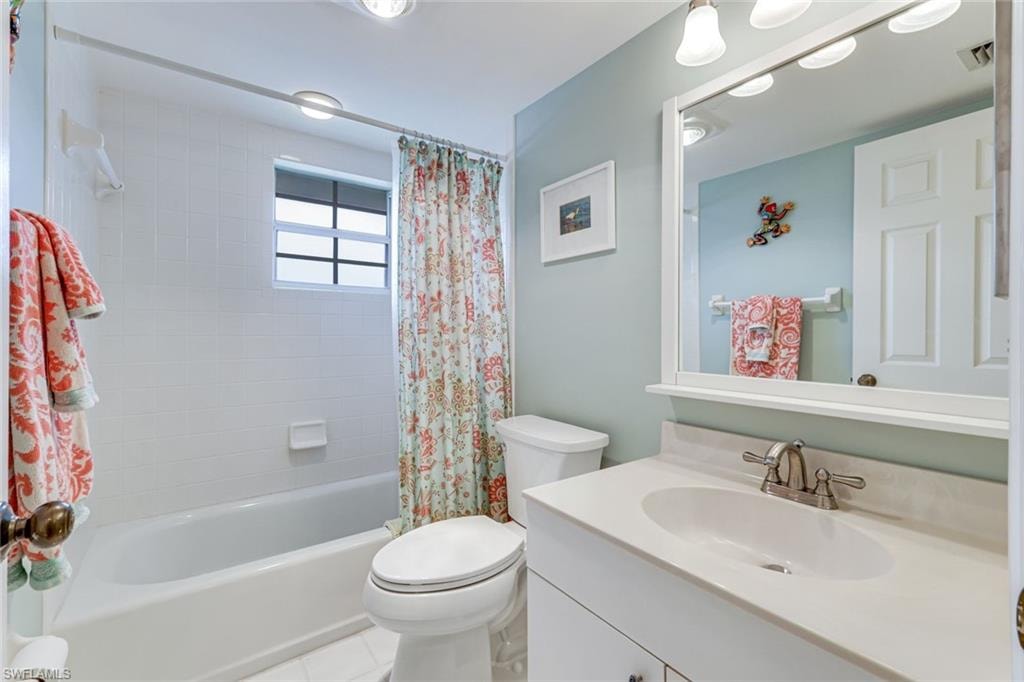 Full bathroom featuring a white vanity with an integrated sink and brushed nickel faucet, a white tub with subway tile surround, and a frosted glass window