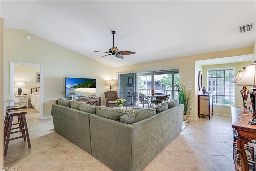 Spacious living area featuring vaulted ceilings, tile flooring, and a ceiling fan