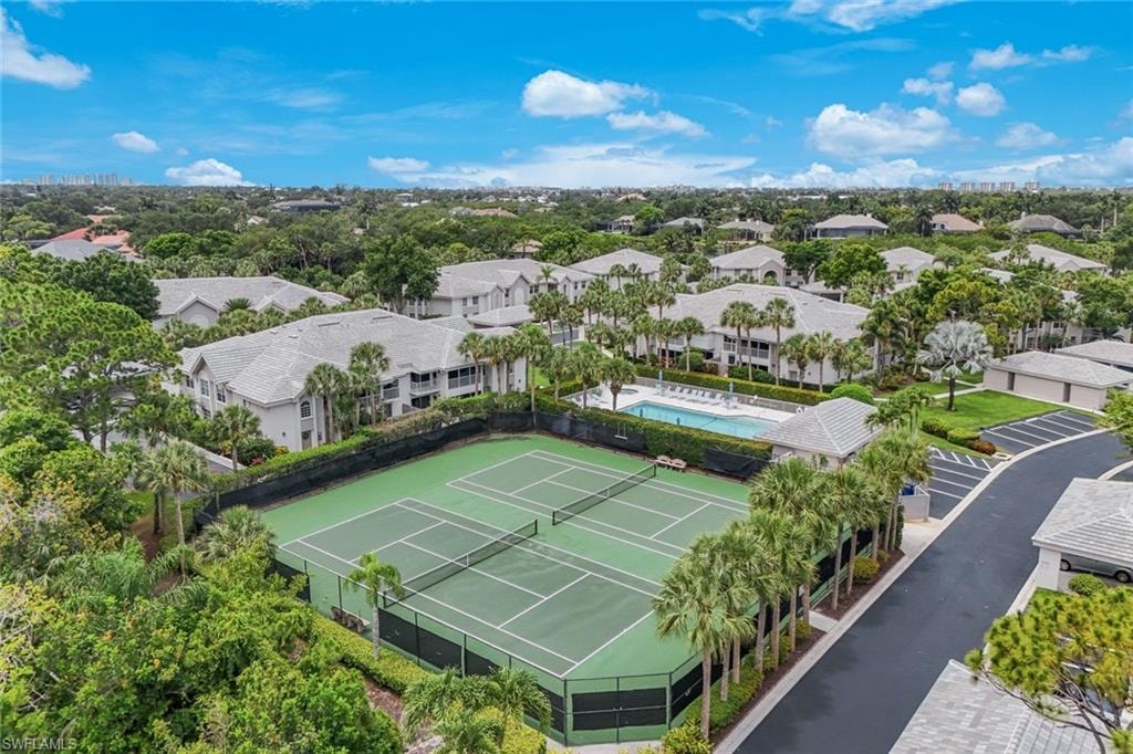 Community amenities featuring a tennis court, a swimming pool with lounge seating, and dedicated parking areas