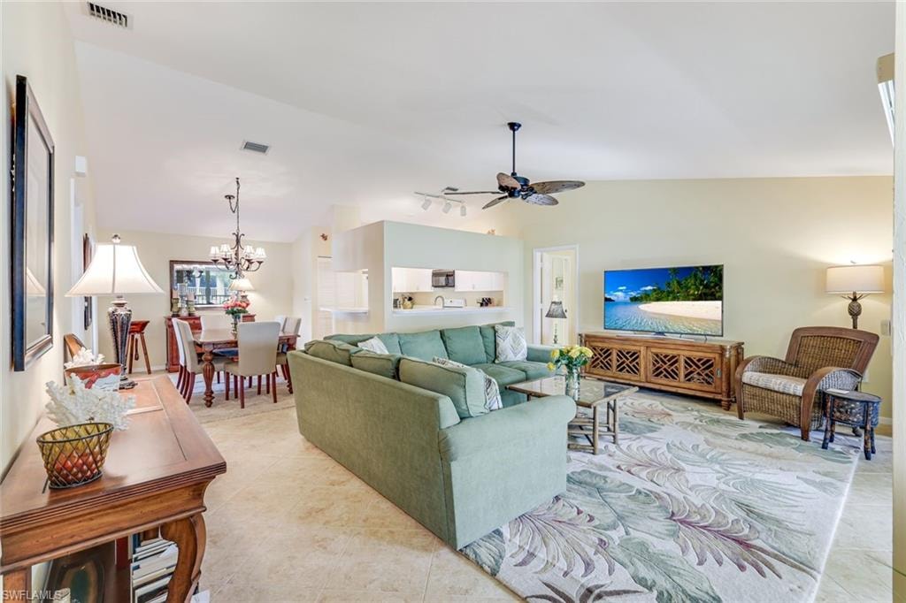 Spacious open-concept living area featuring high vaulted ceilings, light-toned wall finishes, and tile flooring