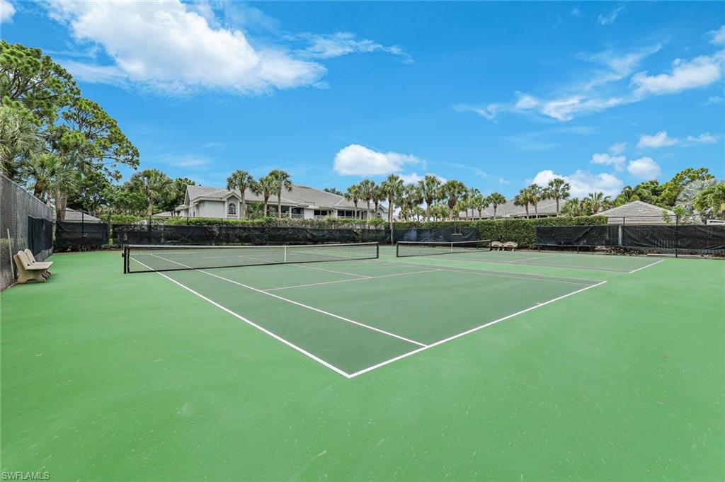 Green-surfaced tennis court featuring a black net and white court lines