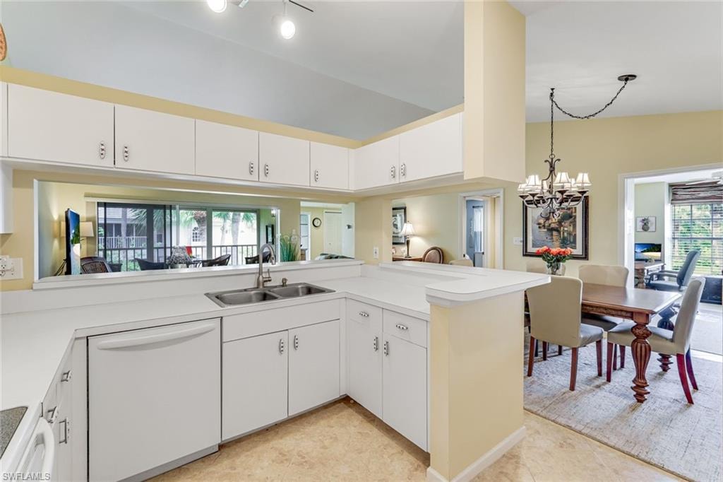 Kitchen with white cabinetry, white countertops, a double basin stainless steel sink, and a pass-through window