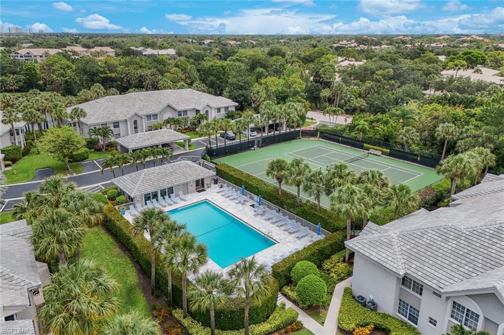 Community amenities featuring a swimming pool, tennis court, and lush tropical landscaping