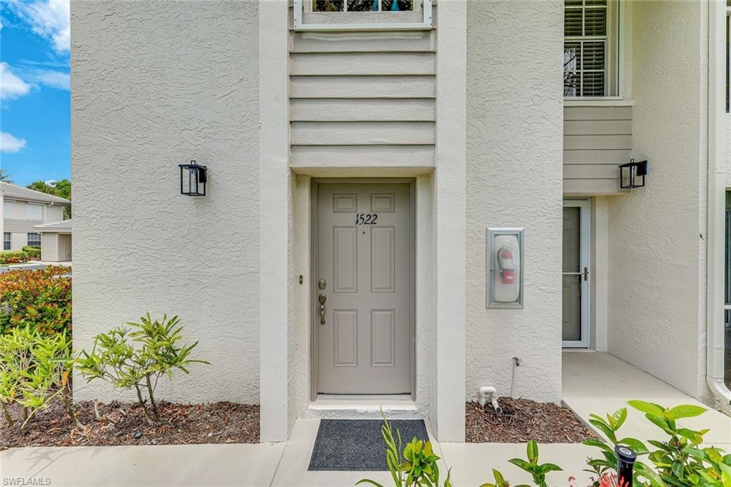 Entryway featuring a painted door with a numeric address placard and black exterior lighting fixtures
