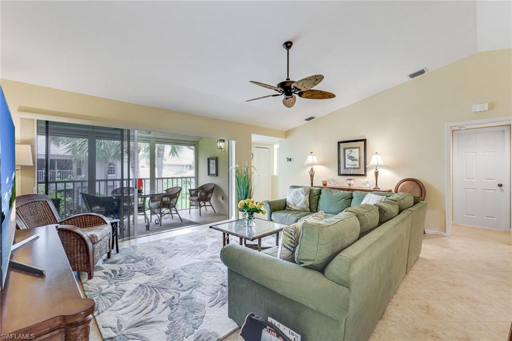 Spacious living area featuring vaulted ceilings, a ceiling fan, and direct access to a screened balcony through sliding glass doors