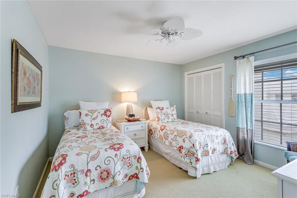 Bedroom with light-colored walls, carpet flooring, a window with blinds, and white louvered closet doors