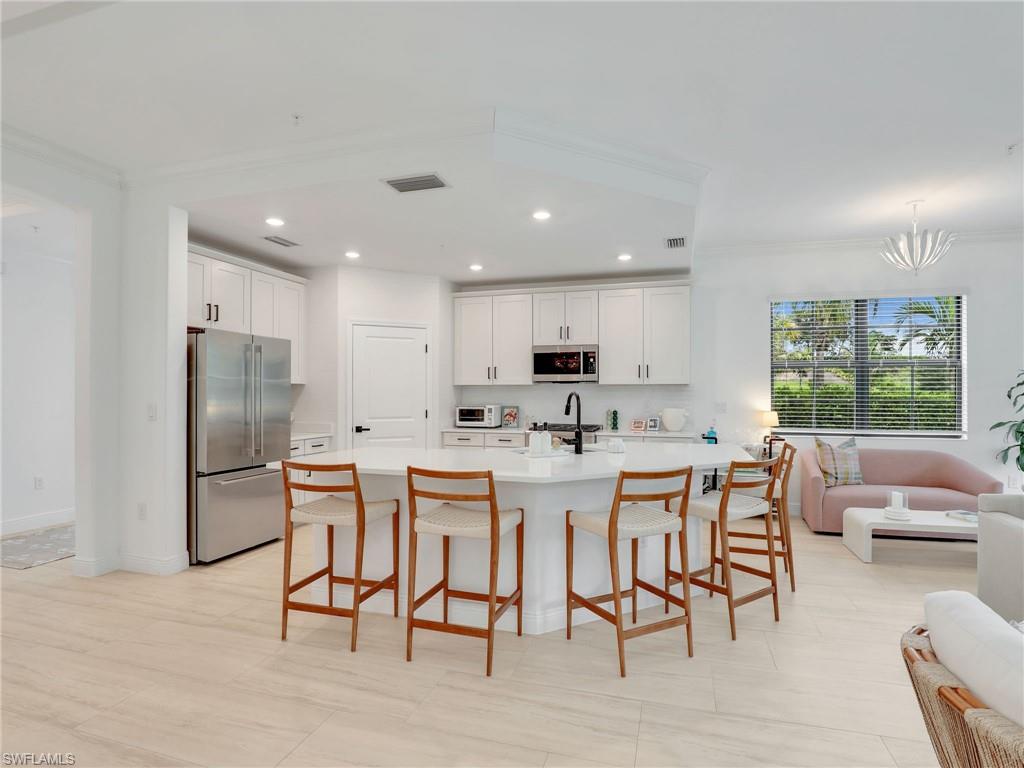 Kitchen with appliances with stainless steel finishes, crown molding, light countertops, recessed lighting, and a breakfast bar