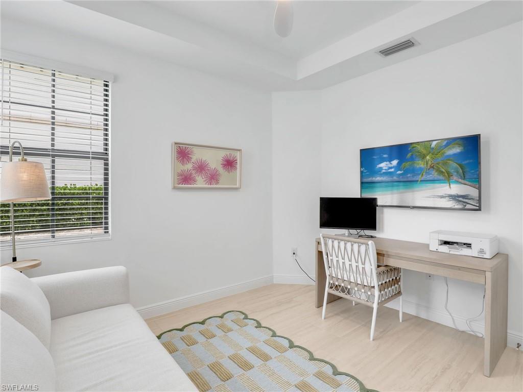 Office space with wood finished floors, baseboards, and a tray ceiling