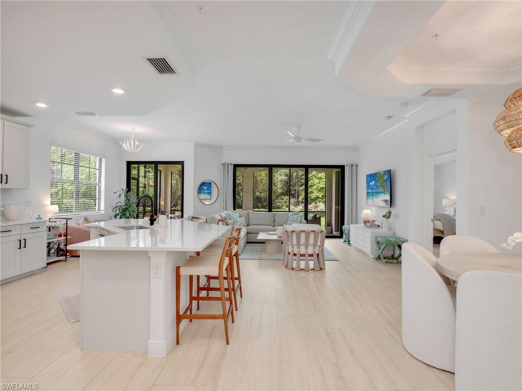 Kitchen with open floor plan, crown molding, light countertops, recessed lighting, and a sink