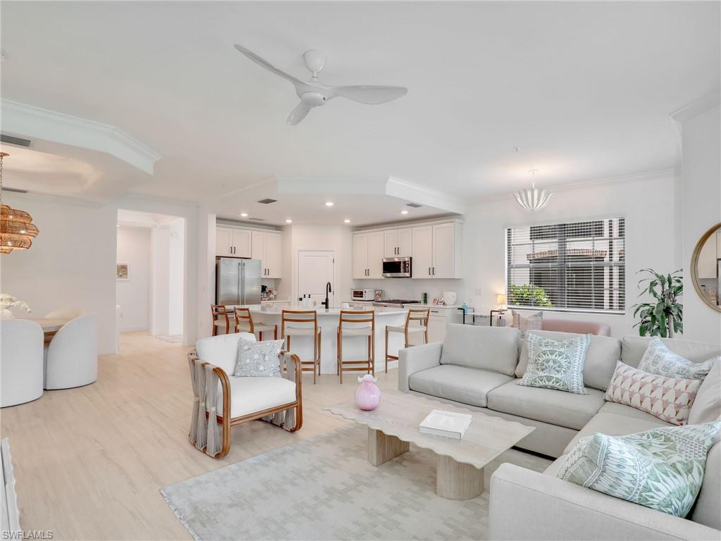 Living room featuring a chandelier, recessed lighting, crown molding, ceiling fan, and light wood-style floors