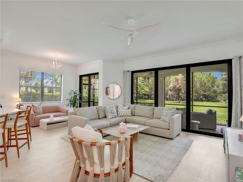 Living area with ornamental molding, a ceiling fan, light tile patterned flooring, and a chandelier