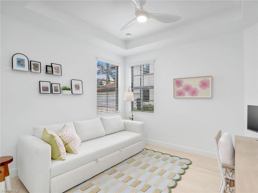 Living room featuring ceiling fan, a tray ceiling, and baseboards