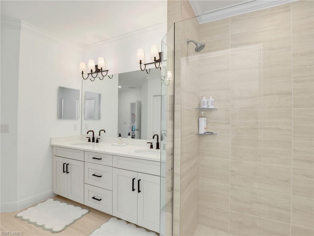 Bathroom featuring double vanity, a shower stall, and crown molding
