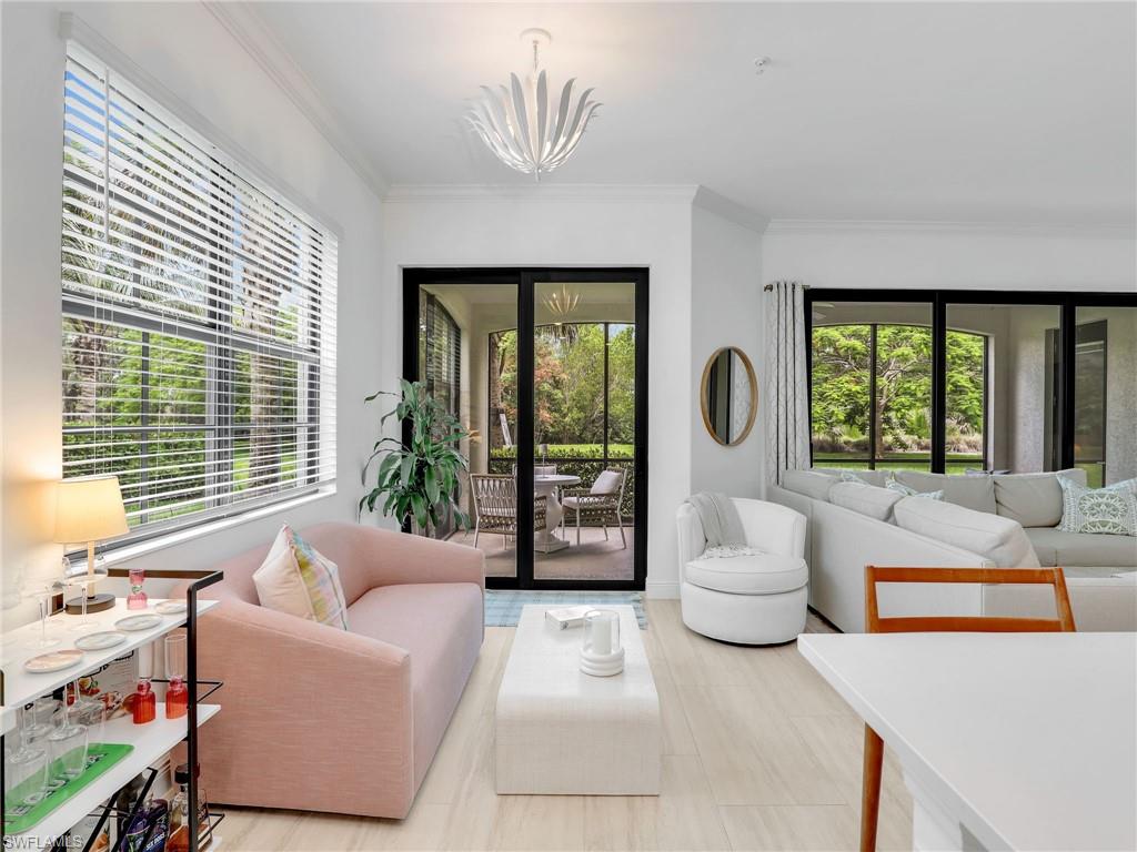 Living area with healthy amount of natural light, crown molding, a chandelier, and baseboards