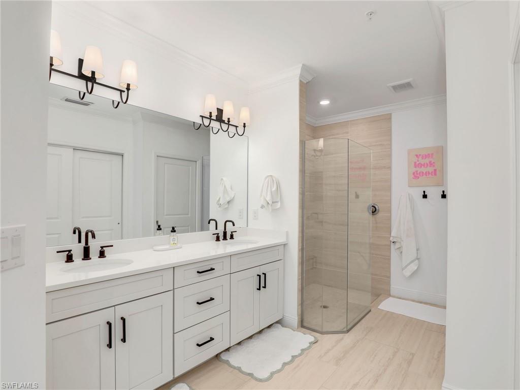 Bathroom with double vanity, a stall shower, baseboards, ornamental molding, and recessed lighting