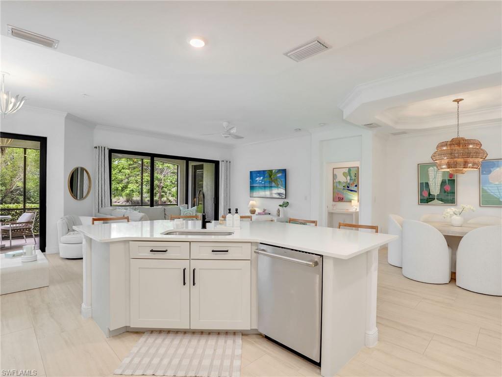 Kitchen with dishwasher, open floor plan, a sink, a chandelier, and ornamental molding