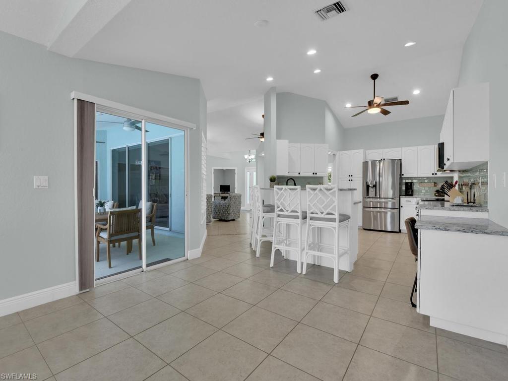 Open-concept kitchen featuring white cabinetry, stainless steel appliances, and a central island with bar seating