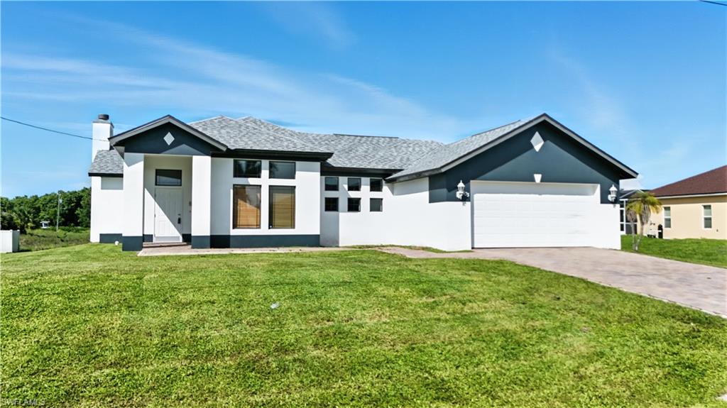 Contemporary stucco exterior with a gray-toned roof, an integrated garage, a paved driveway, and a front yard with established lawn