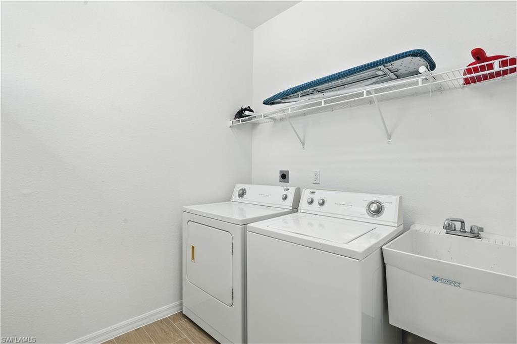 Dedicated utility room featuring a laundry sink, wire shelving, and wood-finish tile flooring