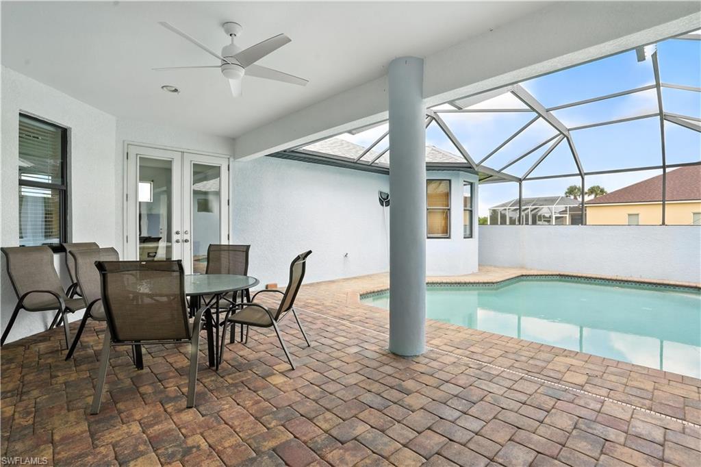 Screen-enclosed pool area featuring a paver patio and a mounted ceiling fan