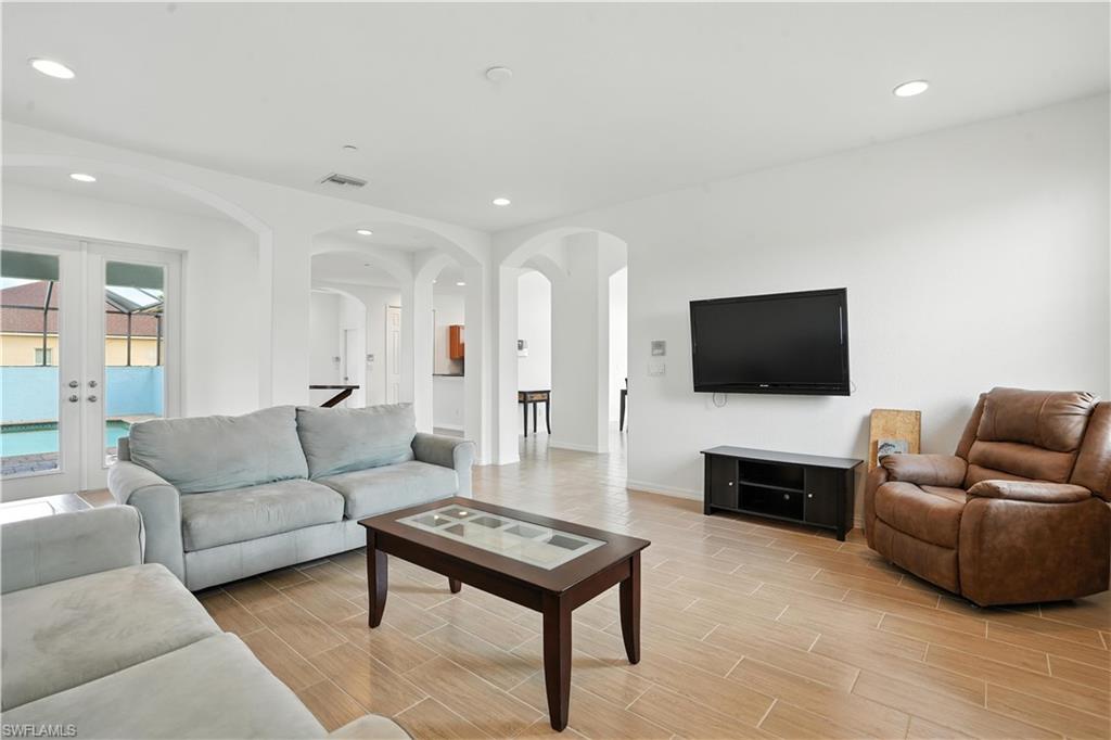 Open-concept living space with wood-finish flooring, recessed lighting, and white walls
