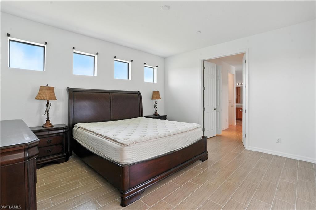 Spacious bedroom featuring light-toned tile flooring, white walls, and a series of high-set rectangular windows
