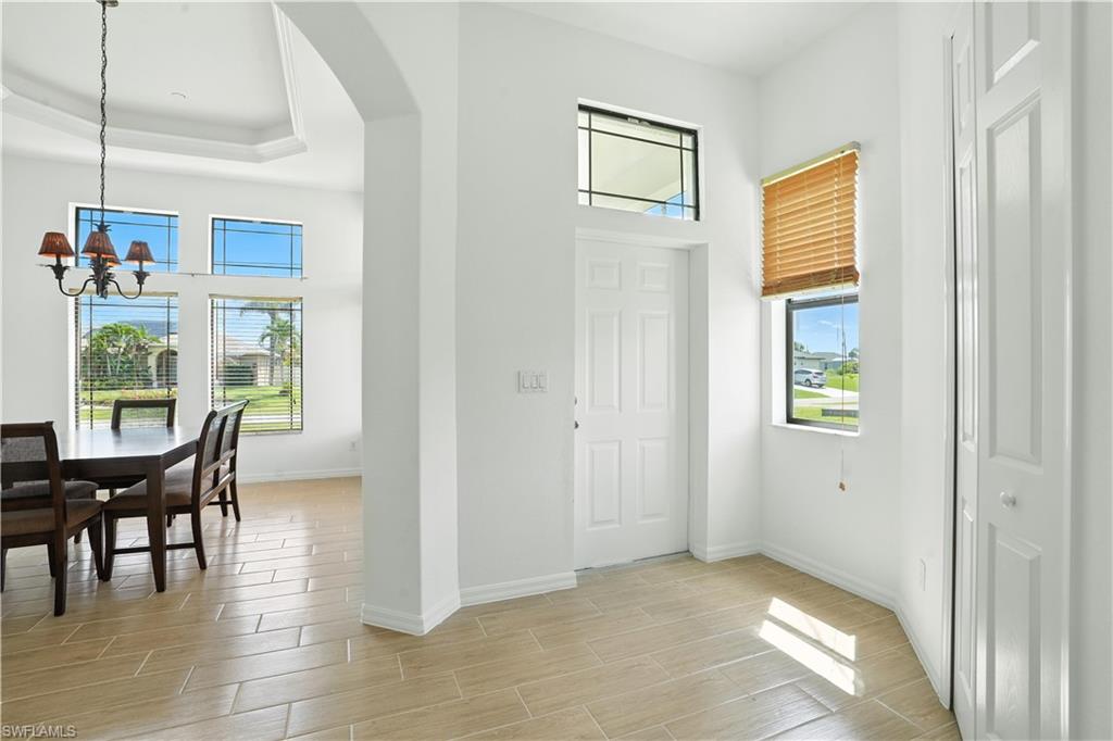 Bright entryway featuring light-toned tile flooring and a white paneled front door with an overhead transom window
