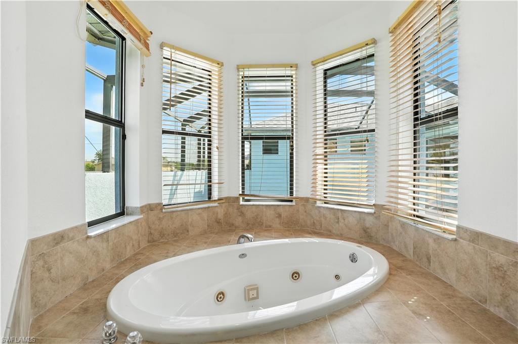 Integrated jetted soaking tub featuring a tiled surround and three bay windows