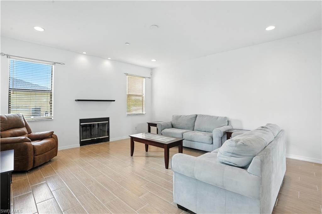 Spacious interior featuring wood-finish flooring, a built-in fireplace with a black glass screen, and recessed lighting