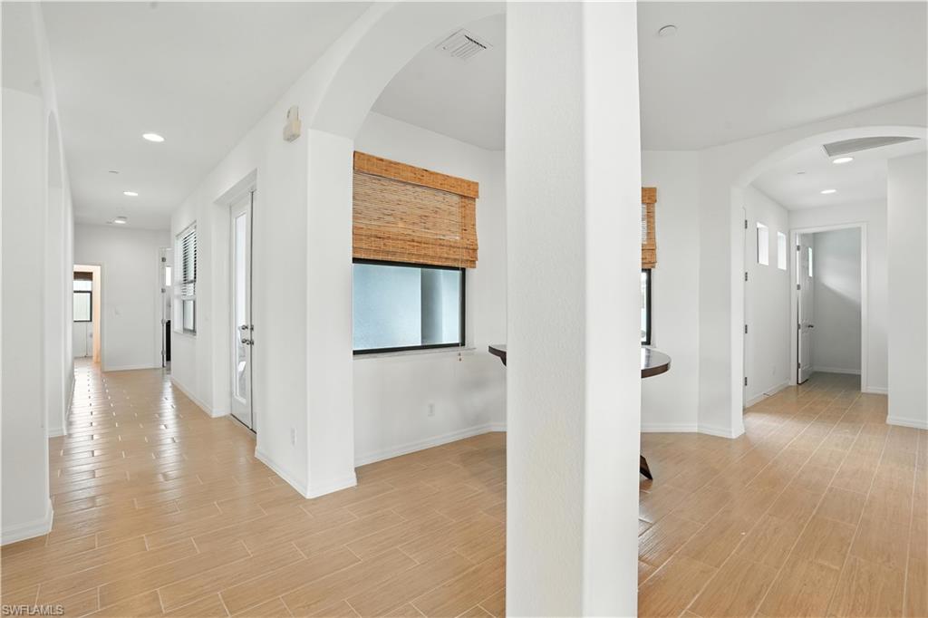 Expansive hallway featuring wood-finish flooring, recessed lighting, and arched doorways
