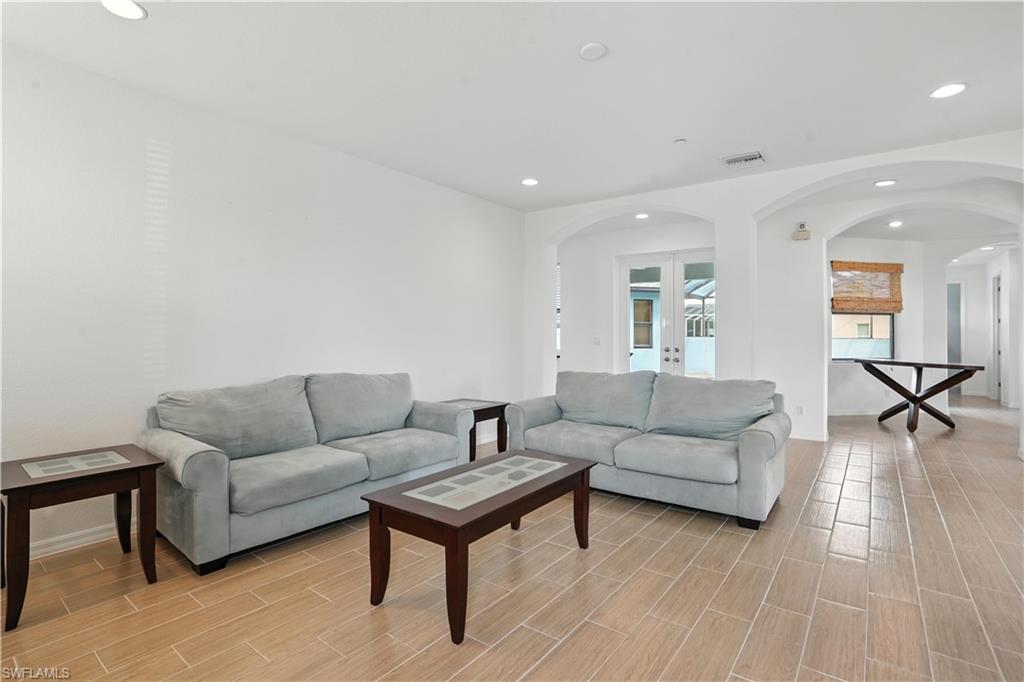 Spacious living area featuring light wood-finish flooring, recessed lighting, and white walls