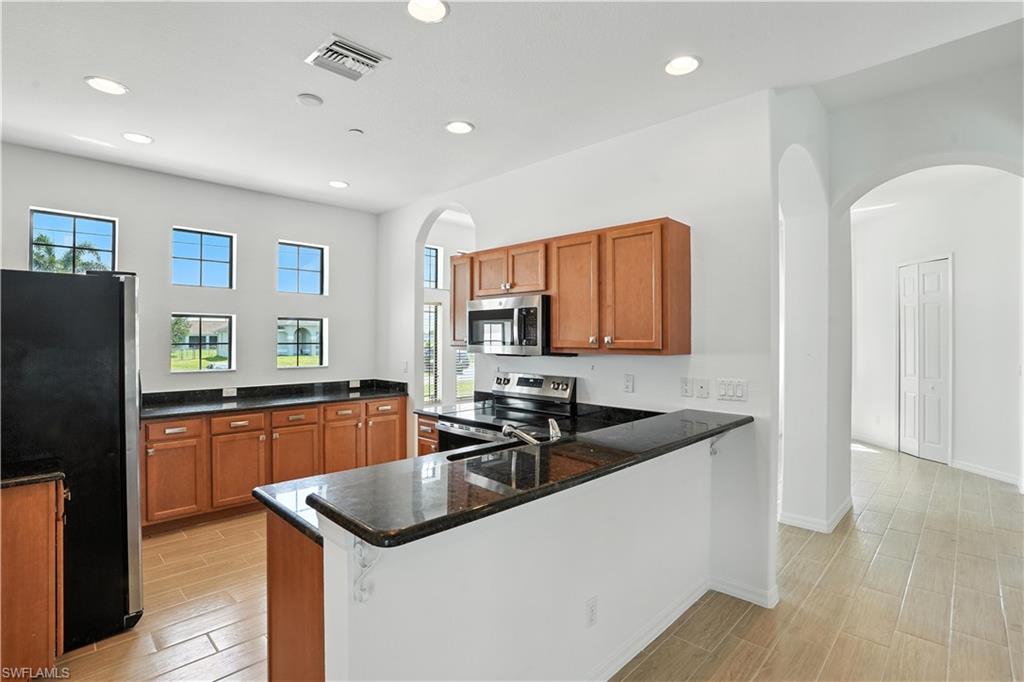 Kitchen featuring wood-finish flooring, dark granite countertops, and wood-tone cabinetry