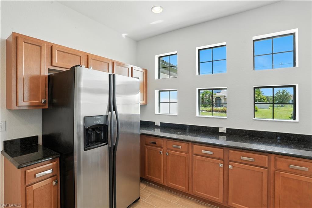 Kitchen area featuring wood cabinetry, dark speckled countertops, and a stainless steel side-by-side refrigerator
