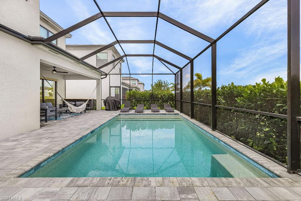 Screened outdoor living area featuring a rectangular pool with integrated steps