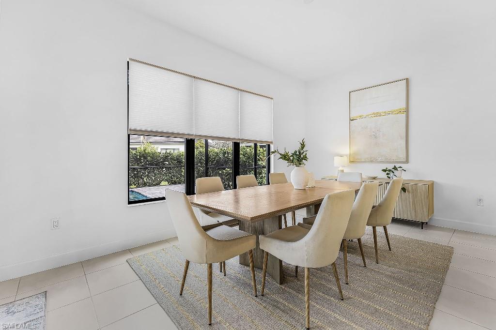 Bright room featuring a large window with privacy blinds, white walls, and light-colored tile flooring