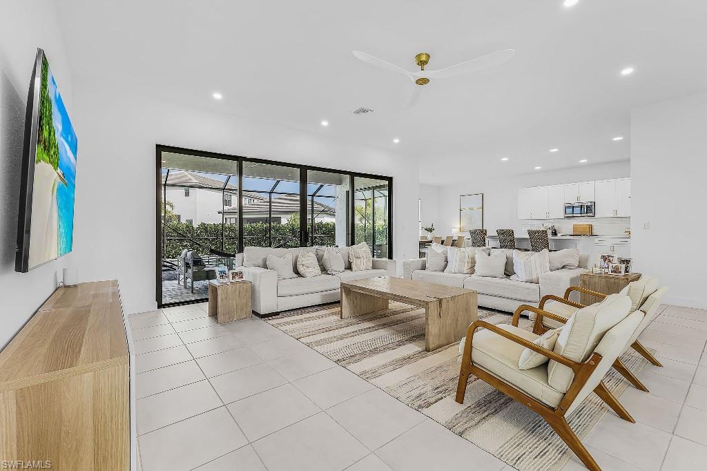 Open-concept living area with white tile flooring, recessed lighting, and a ceiling fan