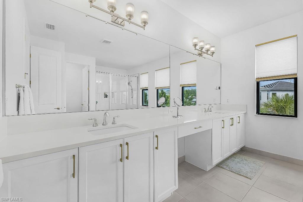 Dual vanity with white cabinetry, gold-finish hardware, and a single-slab countertop