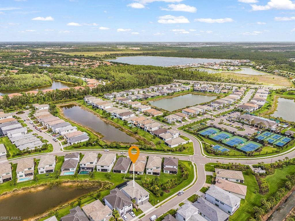 Aerial perspective of a structured residential community featuring numerous homes with distinct architectural styles, waterways, and green spaces