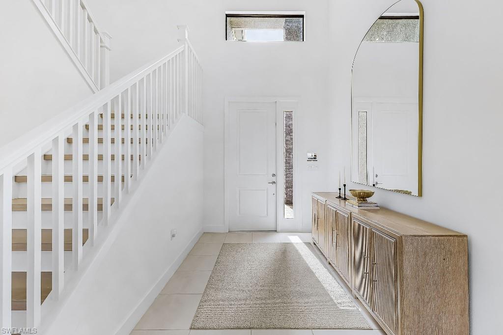 Entryway featuring a white wood staircase with natural wood treads, ceramic tile flooring, and a transom window above the front door