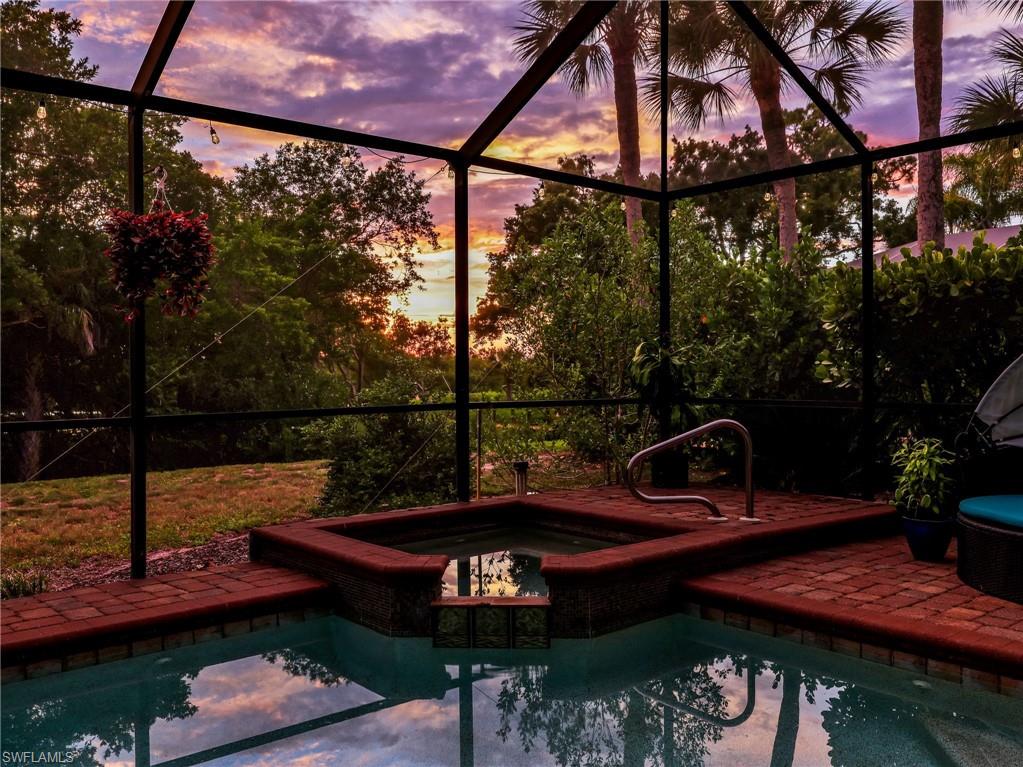Screened enclosure featuring a geometric pool and integrated spa with brick coping