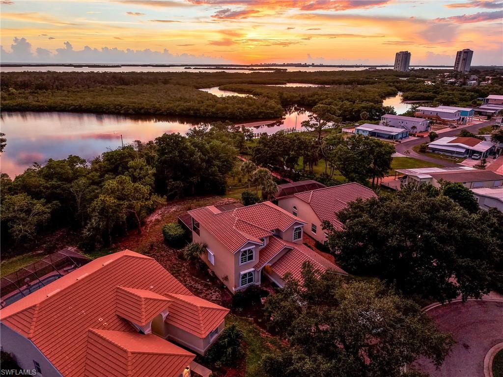 Red tile roofs characterize this property and surrounding homes, situated among mature trees