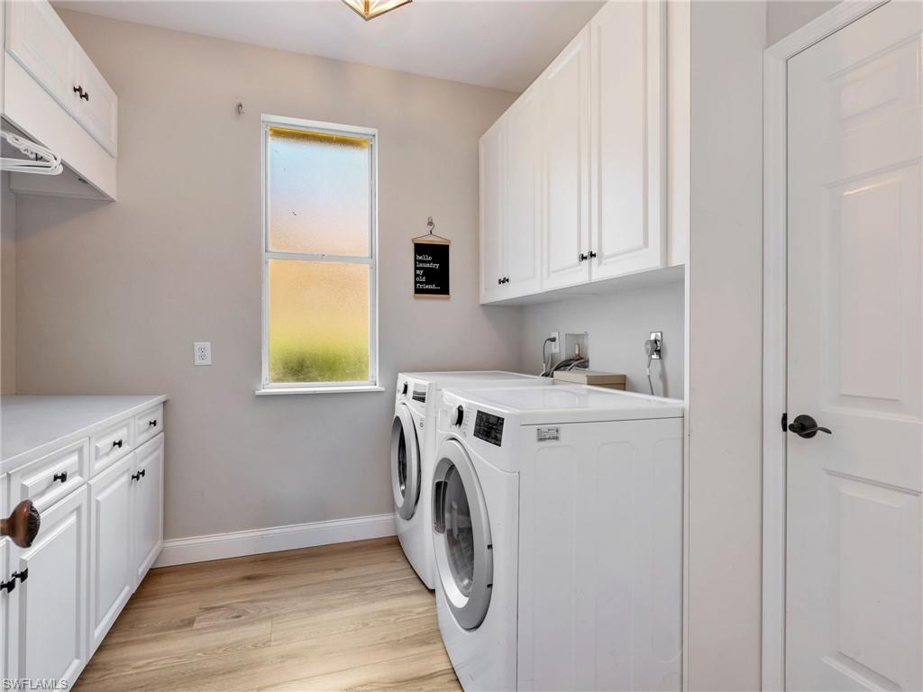 Dedicated laundry space featuring white shaker-style cabinetry, wood-finish flooring, a rectangular window, and a built-in counter