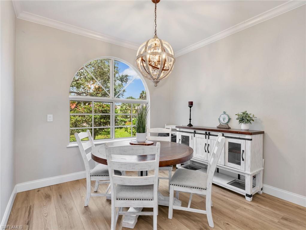 Arched window with divided lites, crown molding, wood-finish flooring, and a unique spherical light fixture