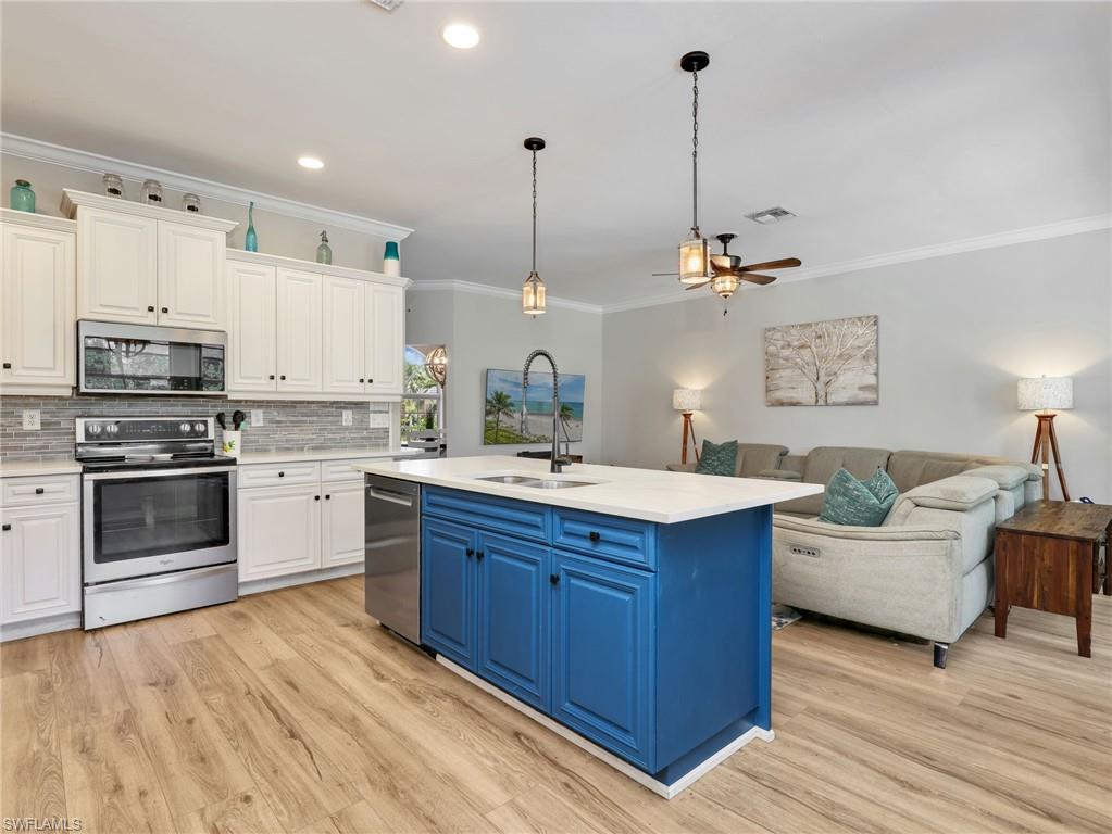 Open-concept kitchen featuring a vibrant blue island with a white countertop and pendant lighting