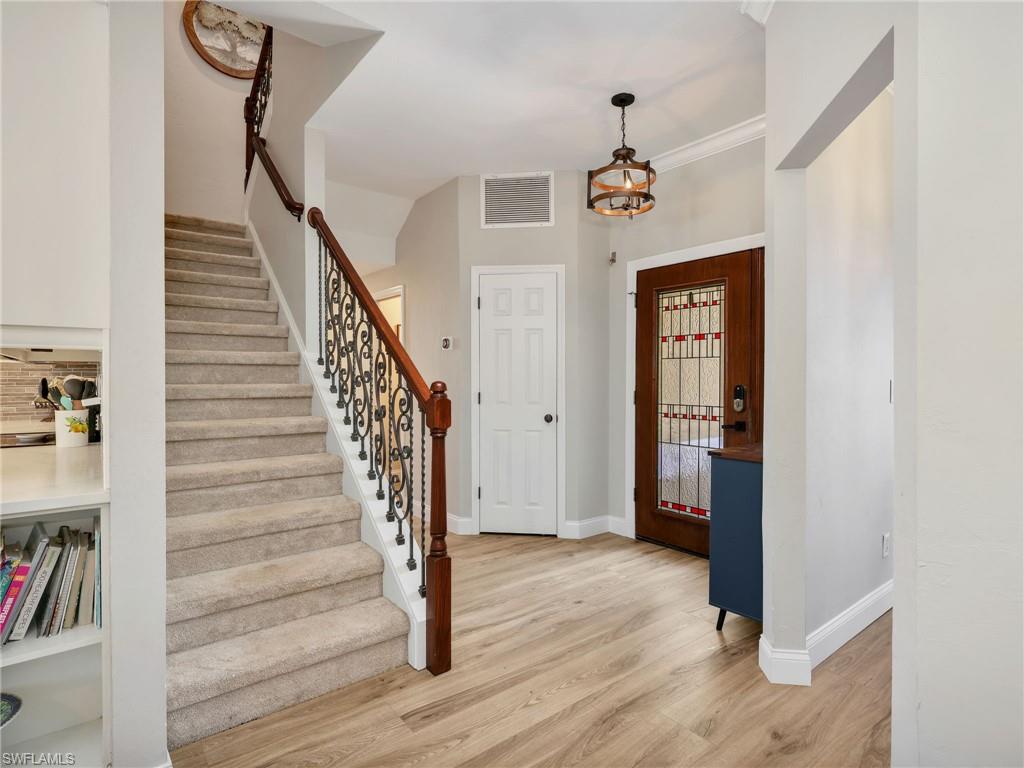 Entryway featuring wood-finish flooring, a decorative stained-glass front door, and a staircase with a wrought-iron and wood railing