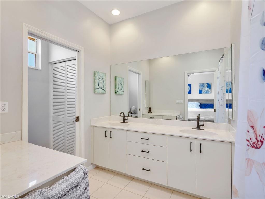 Bathroom featuring a double vanity with white cabinetry, light-toned countertops, and matte black fixtures