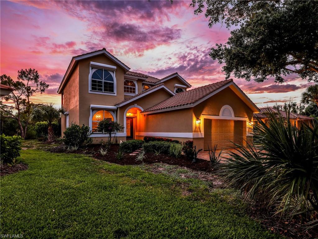Two-story residence featuring a terracotta tile roof, stucco exterior, arched windows, and a two-car garage